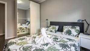 Une chambre à coucher comprenant un lit, une table de chevet, une lampe, un miroir et une armoire.