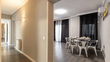 A hallway with a radiator, a dining area with a table and chairs, and a window with curtains.