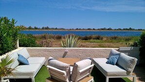 Un patio con mobiliario blanco para exteriores y vista al mar.