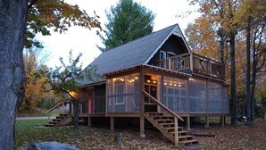 Een chalet met een houten terras, een trap en sfeerverlichting.