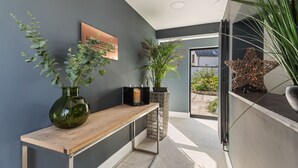 A modern hallway with a wooden bench, a green vase, a framed picture, and a decorative star-shaped object. - No1 Highpoint -Luxury 2 bed Sea view Apartment with onsite indoor swimming pool (Saundersfoot)