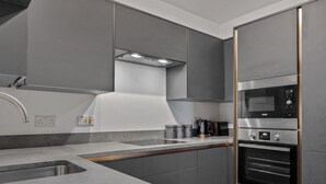 A modern kitchen with grey cabinets, a stainless steel sink, and a built-in oven. - No1 Highpoint -Luxury 2 bed Sea view Apartment with onsite indoor swimming pool (Saundersfoot)
