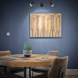 Une table de salle à manger ronde en bois, sur laquelle sont posés un vase aux motifs noir et blanc et une plante en pot.