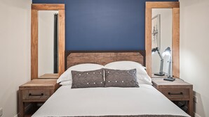 A bed with a wooden headboard, two nightstands with drawers, and a mirror on each side. - No1 Highpoint -Luxury 2 bed Sea view Apartment with onsite indoor swimming pool (Saundersfoot)