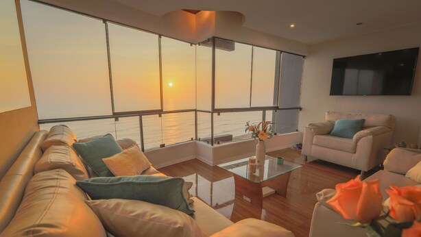 A living room with a sofa, armchairs, a coffee table, and a TV. - Exclusive oceanfront Penthouse in Miraflores with rooftop terrace (Urb Santa Cruz)