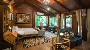 A wooden interior with a bed, a sofa, a coffee table, and a chandelier. - Cattani's Riverside Home (Ayutthaya)