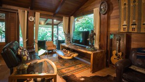 A cozy living room with a leather sofa, a glass coffee table, a wooden desk, and a guitar. - Cattani's Riverside Home (Ayutthaya)