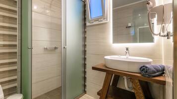 Ein modernes Badezimmer mit Duschkabine aus Glas, Waschtisch aus Holz und großem Spiegel.