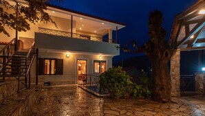 A two-story building with a balcony, stone steps, and a tree in the foreground. - Villa Kleinos: A truly magnificent villa 30 minutes from Meteora Greece (Kalambaka)