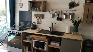 Una cocina compacta con estufa, microondas, pileta y diferentes utensilios.