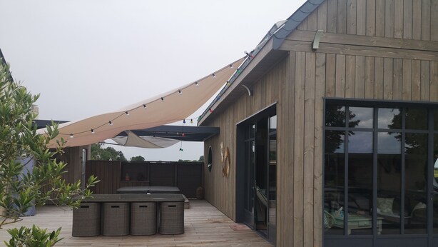 Una terraza de madera con una zona de estar cubierta y un amplio ventanal.