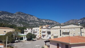 A building with multiple floors, balconies, and a parking area in front. - Attic with sea view just 30 meters from the beaches with parking space in the courtyard! (Cala Gonone)