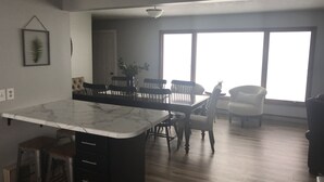 A modern kitchen with a marble countertop, wooden dining table, and chairs. There is a large window providing natural light. - Oak & Arrow Cabin On Bluedog Lake, Waubay - Hunting, Fishing, Vacation (Waubay)