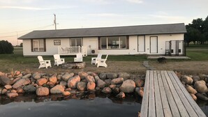 A house with a porch, outdoor seating, and a dock over water. - Oak & Arrow Cabin On Bluedog Lake, Waubay - Hunting, Fishing, Vacation (Waubay)