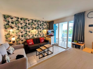 Une chambre d’hôtel avec un canapé, un lit, une télévision, une petite table et un balcon avec vue.