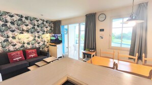 Una sala de estar moderna con un sofá, un televisor, una mesa de comedor y una zona de cocina.