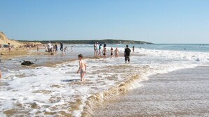 Una playa con gente caminando por la orilla.