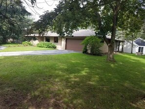 Uma casa com gramado frontal, entrada para carros e garagem.