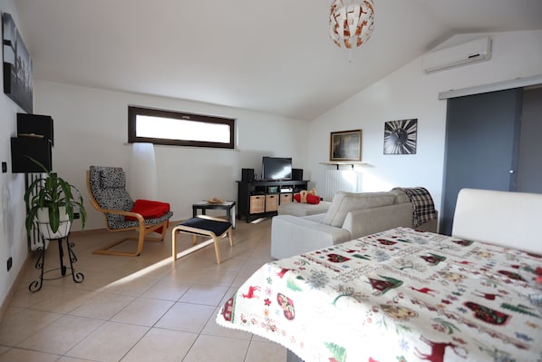 Una sala de estar moderna con un sofá, una silla, un televisor y una mesa decorativa.