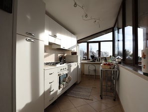 Cocina moderna con armarios blancos, estufa a gas y un amplio ventanal con vistas al exterior.