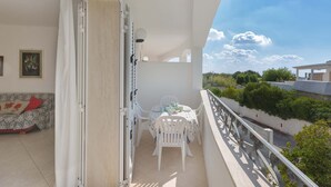 Een balkon met een tafel en stoelen, een bank en uitzicht op de omgeving.