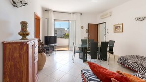Ein modernes Wohnzimmer mit Essbereich, Fernseher und Balkon mit Blick.