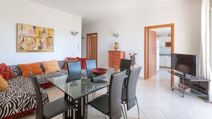 Ein modernes Wohnzimmer mit einem Glastisch, schwarzen Stühlen, einem Sofa mit ZEBRA-Muster und einem großen abstrakten Gemälde.