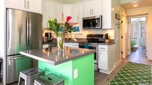 Une cuisine moderne avec des armoires blanches, des appareils en acier inoxydable et un mur d’accent vert.