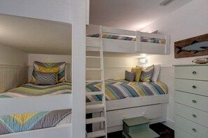 A bunk bed room with a ladder, a dresser, and a wall-mounted shelf.