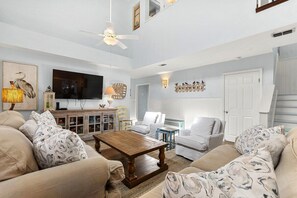Ein Wohnzimmer mit Fernseher, Deckenventilator und Kamin.