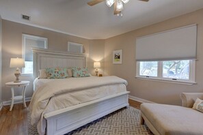 Ein Schlafzimmer mit einem Bett, Nachttischen, einem Deckenventilator und einem Fenster mit Jalousien.