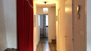 A hallway with wooden flooring, a red curtain, and a chandelier.