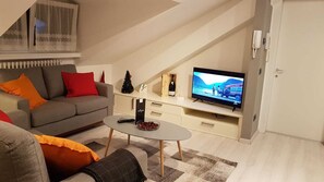 Una sala de estar con un sofá, una mesa de centro, televisor y un pequeño árbol de Navidad.