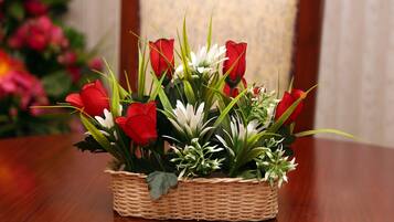 Un cesto di vimini pieno di fiori rossi e bianchi appoggiato su un tavolo di legno.