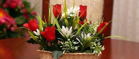 A wicker basket filled with red and white flowers placed on a wooden table.