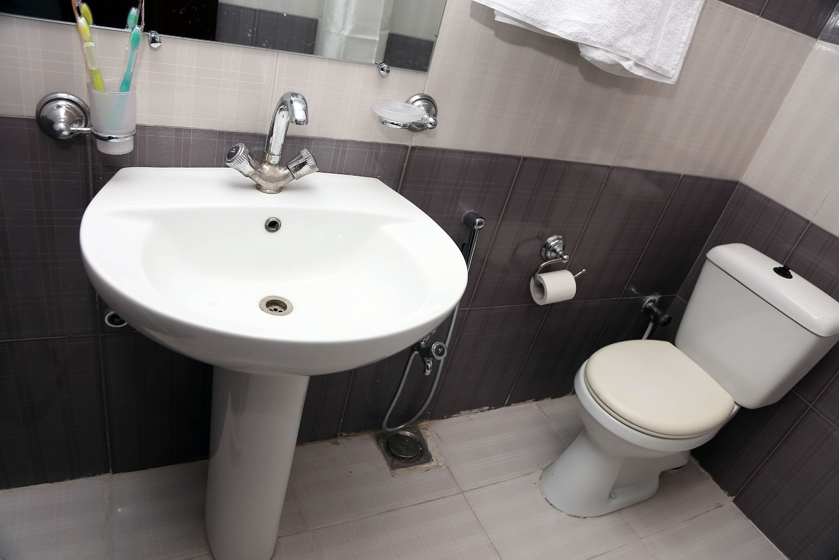 Une salle de bain avec un lavabo blanc, des toilettes et un miroir.