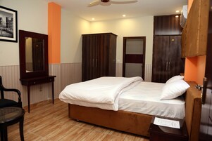Un dormitorio con cama, un armario de madera, un espejo y una silla.