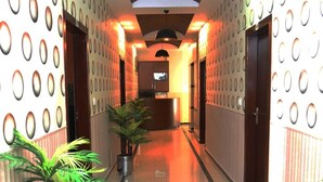 A hotel corridor with a polished floor, potted plants, a reception desk, and patterned walls. - Hak Mall Suites (Rawalpindi)