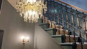Eine moderne Treppe mit einem Chandelier und einem Geländer mit aufwendigen Mustern.