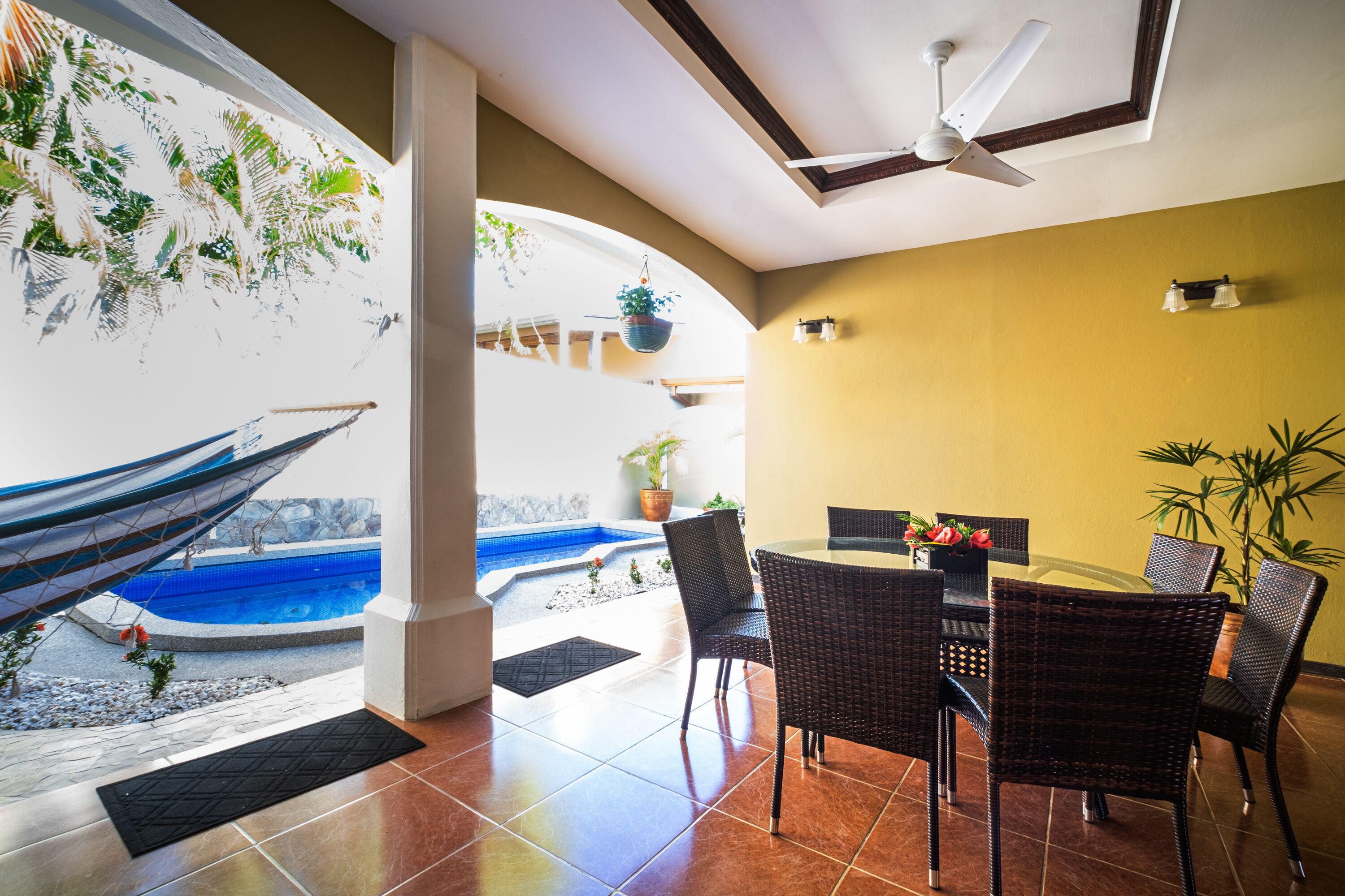A dining area with a table and chairs, a ceiling fan, and a view of a swimming pool.