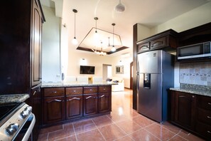A modern kitchen with dark wood cabinets, a stainless steel refrigerator, and a granite countertop.