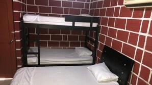 Una habitación con dos literas, una cama individual y una puerta.