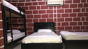 Habitación tipo dormitorio con literas, una cama individual y aire acondicionado instalado en la pared.