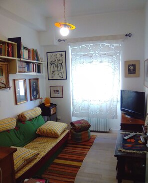 A cozy living room with a sofa, a television, and a bookshelf filled with books.