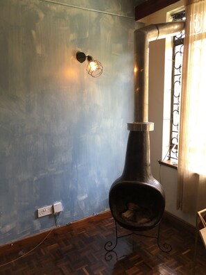 Quarto com uma lareira grande, luminária fixada na parede e janela com grades de ferro decorativas.