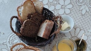 Een tafel met een mand vol brood, een schaal boter, een fruitmand en potten jam en honing.