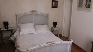 Een slaapkamer met een wit bed, twee nachtkastjes en een deur.