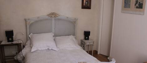 A bedroom with a white bed, two bedside tables, and a door.