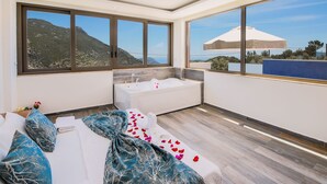 A modern bathroom with a bathtub, large windows, and a view of the mountains.