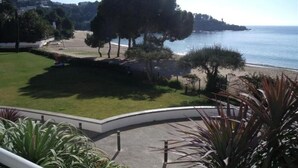 A coastal view with a grassy area, trees, and a beach. - Agi Almadraba 2212 Apartamento for rent in Roses Girona. (Roses)